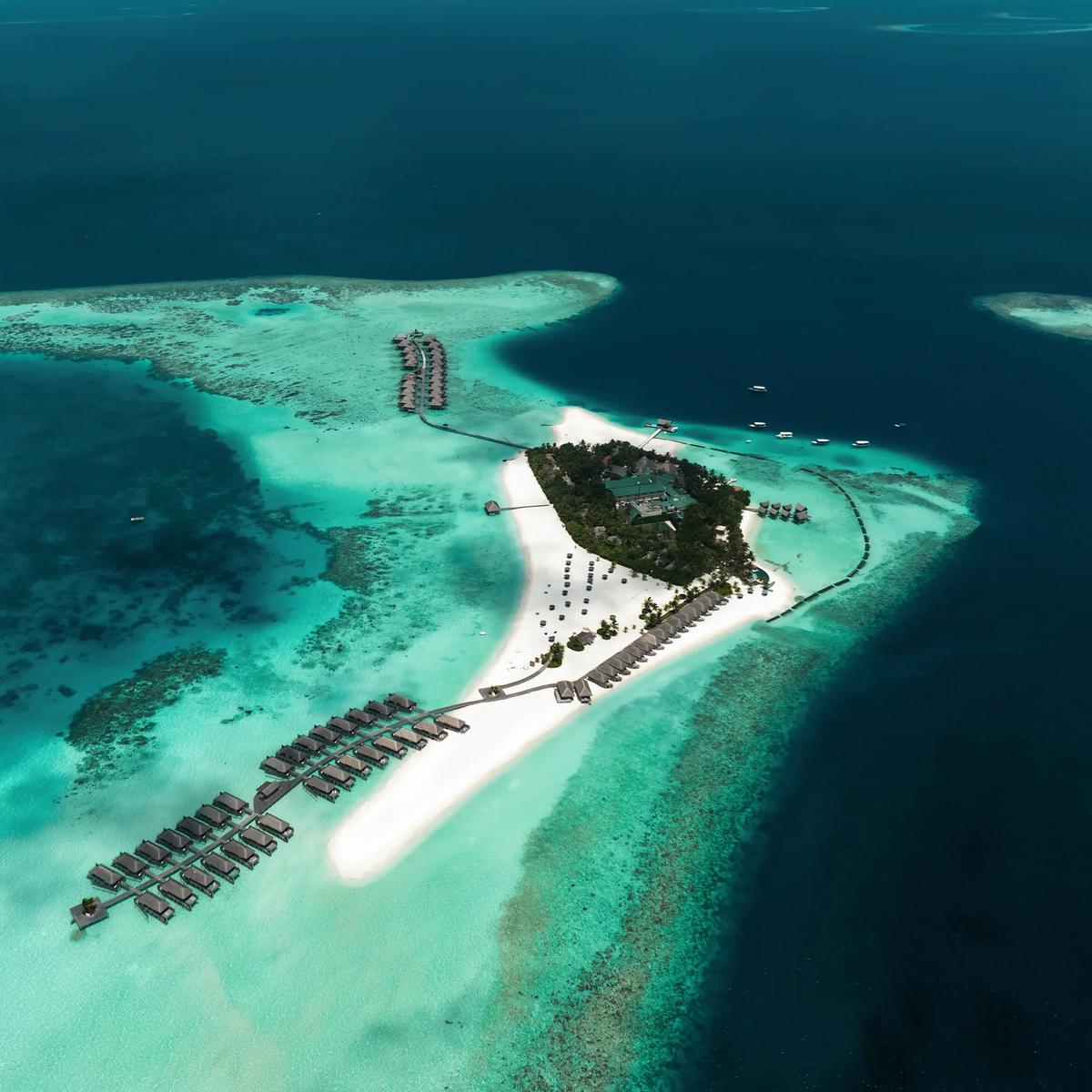 Aerial view of Constance Moofushi's triangular island, its beach and water villa jetties reaching into the South Ari Atoll lagoon