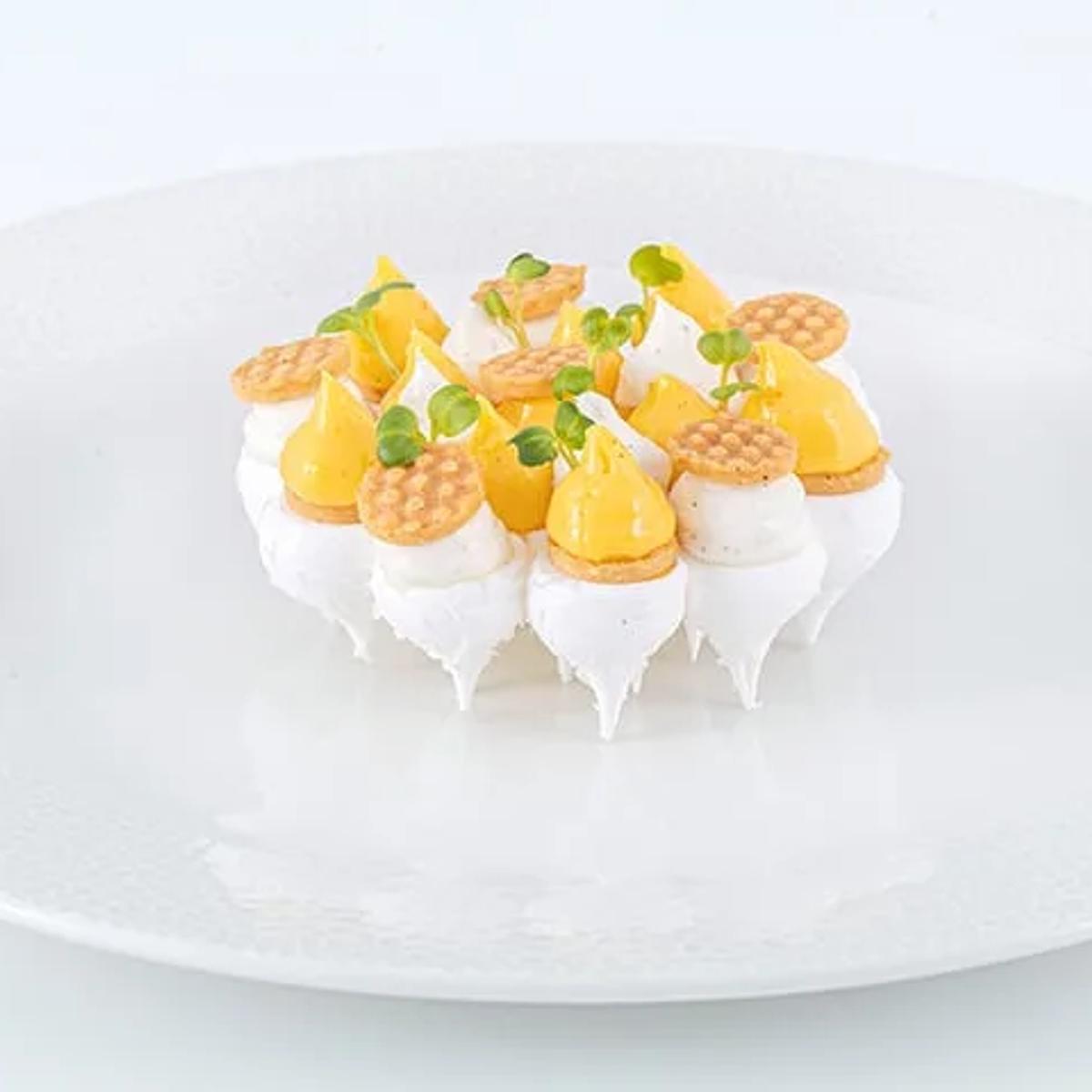 A dessert plate of meringue, mango, and thin golden wafers, plated for in-house dining