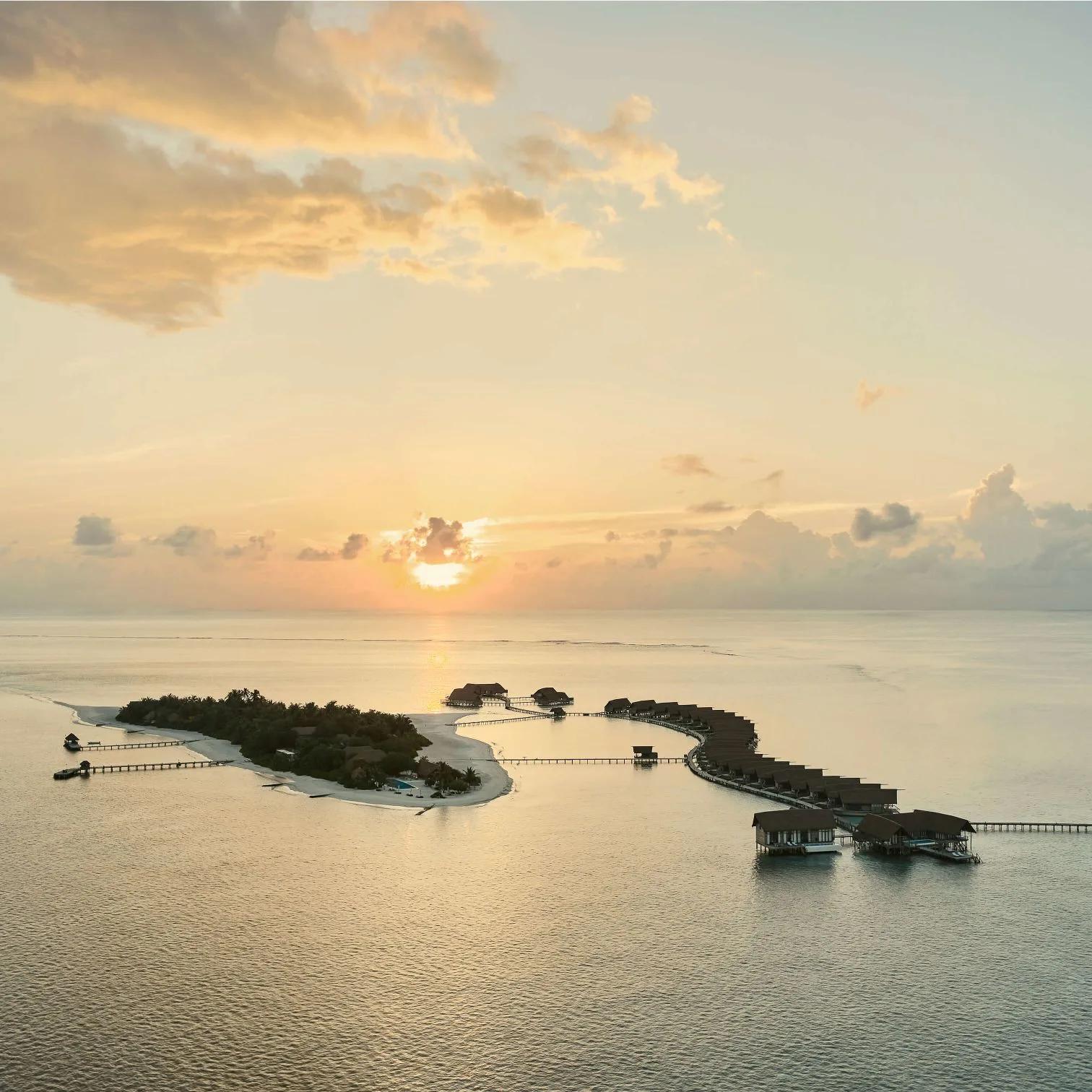 COMO Cocoa Island at dusk, the private island of Makunufushi with its overwater villa jetty stretching into the lagoon