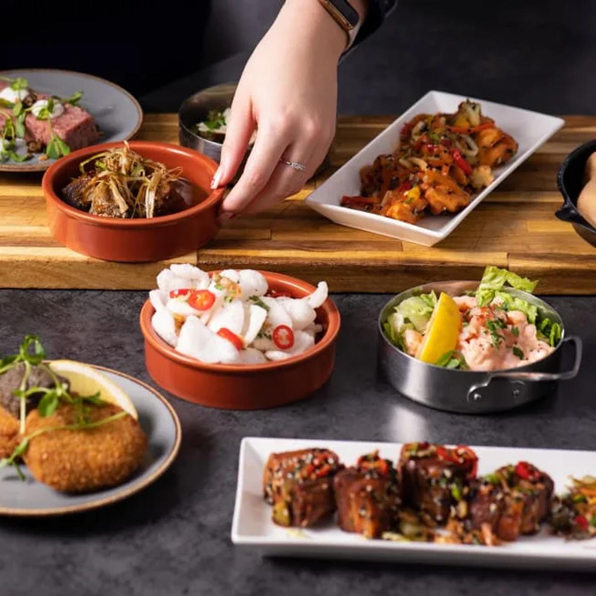 A spread of tapas dishes including seared beef, crab cakes and prawns at Dhoni Bar
