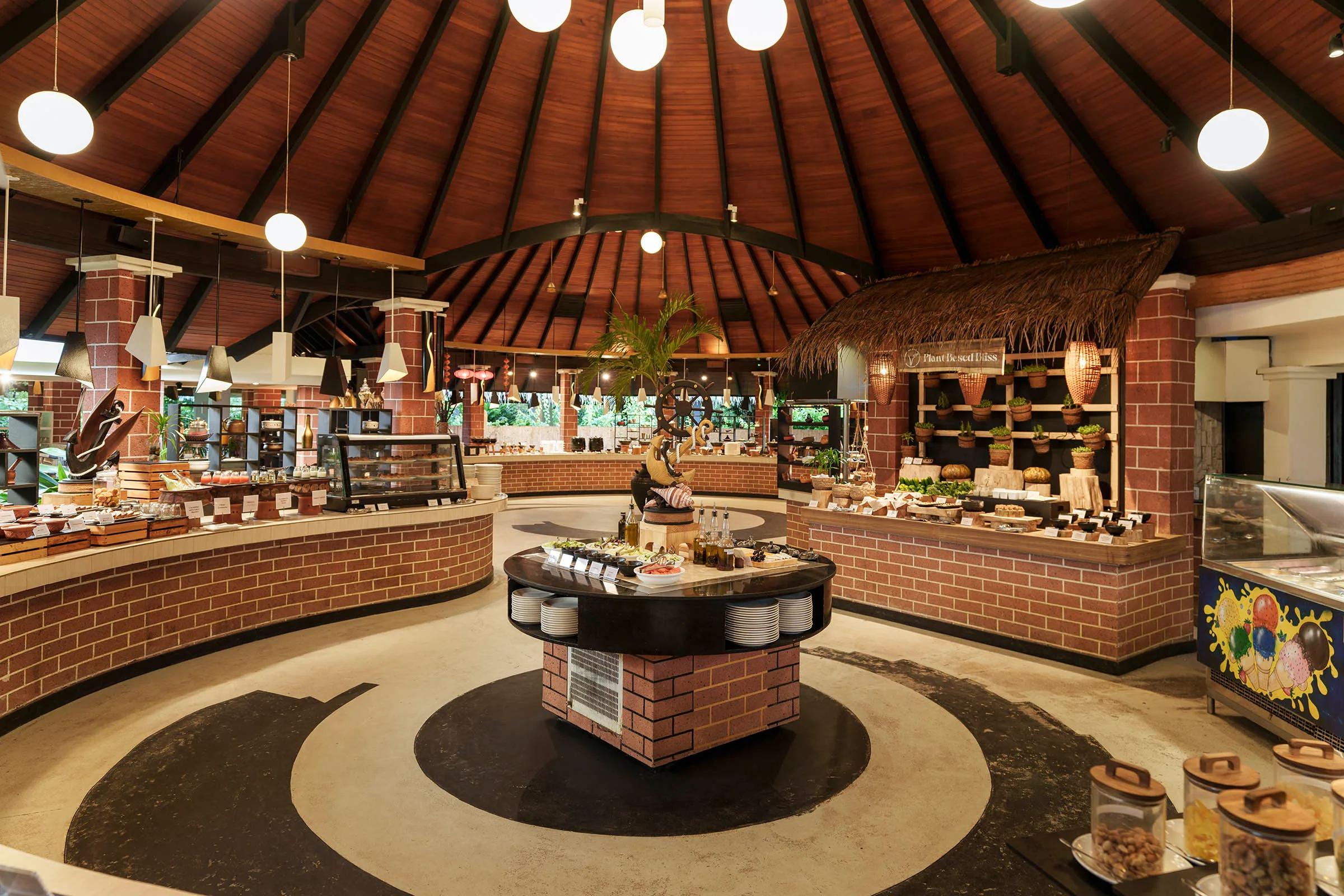 A buffet counter with a 'Plant Based Bliss' station of vegetable dishes under a thatched canopy, representative of Iru Fushi's plant-based dining — dedicated Spa Café photography to follow