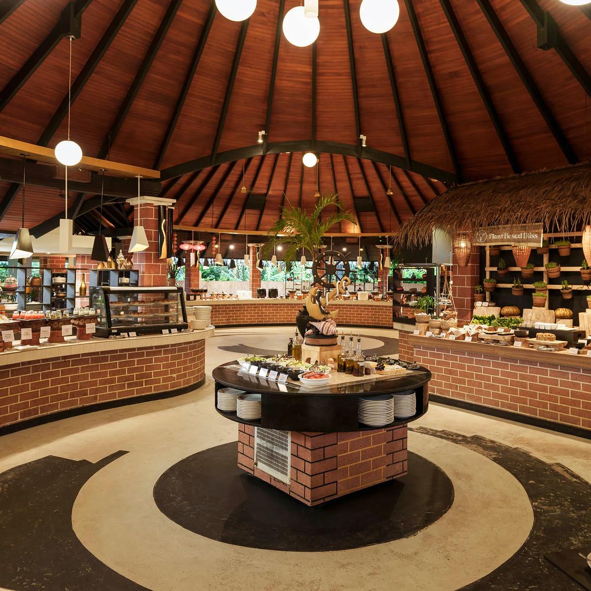 A buffet counter with a 'Plant Based Bliss' station of vegetable dishes under a thatched canopy, representative of Iru Fushi's plant-based dining — dedicated Spa Café photography to follow