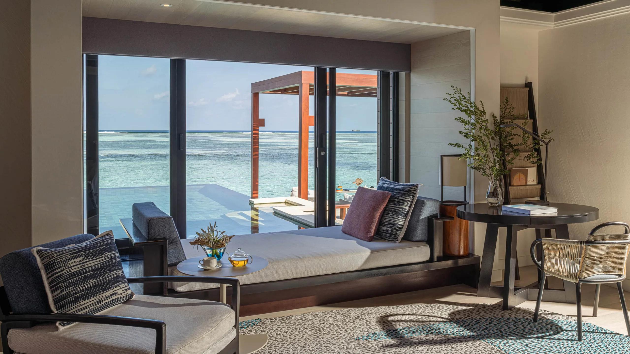 A daybed inside a Sunrise Water Villa, looking out over the plunge pool to open water