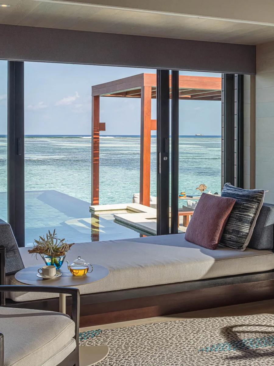 A daybed inside a Sunrise Water Villa, looking out over the plunge pool to open water