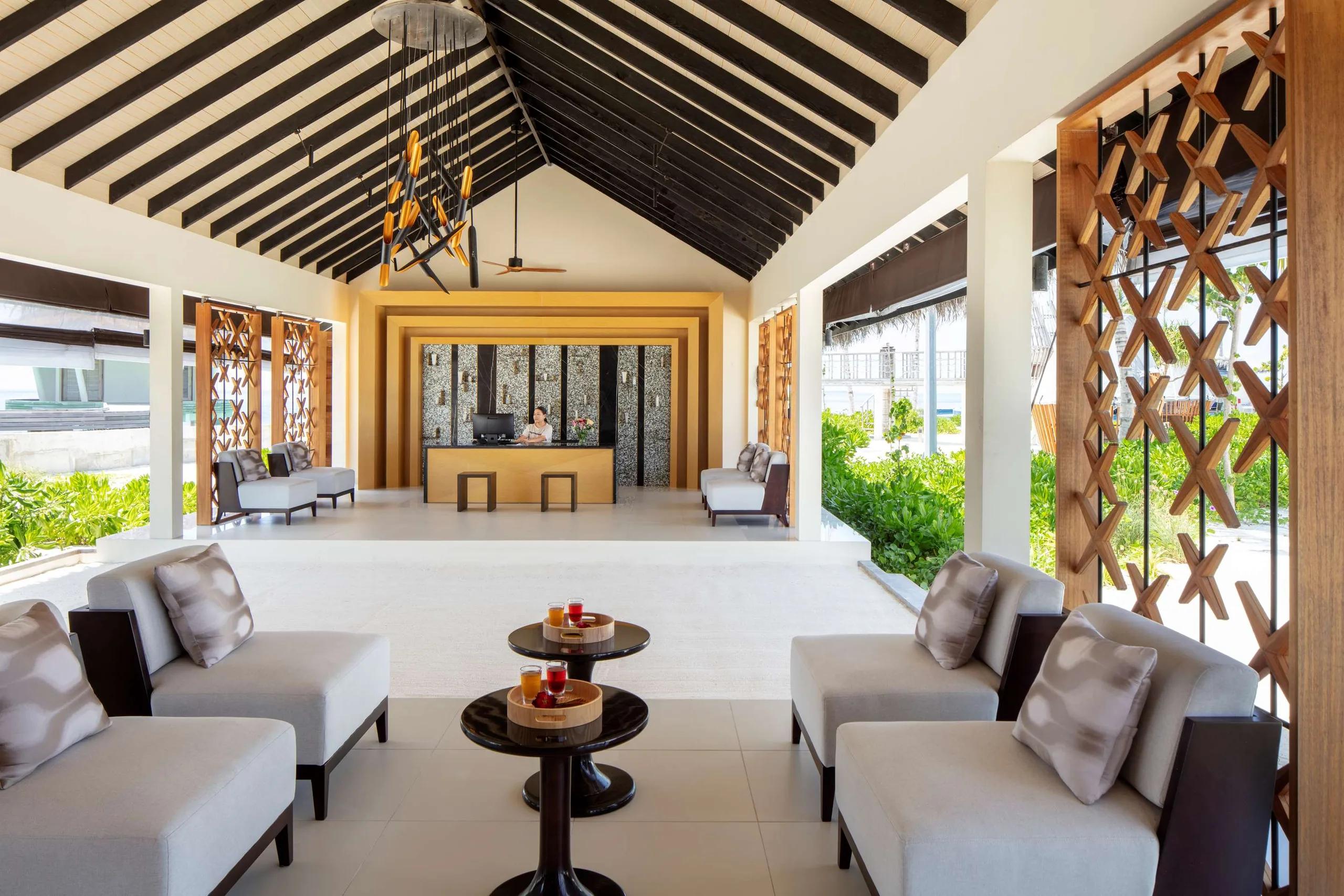 Blu Spa's open-air reception at Radisson Blu Resort Maldives, seating either side of a timber welcome desk