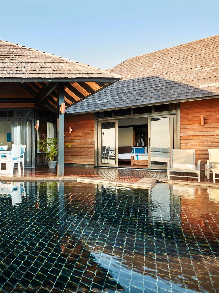 Twin bedroom pavilions of an Aqua Retreat villa facing each other across a shared black-tiled pool and open-air dining deck