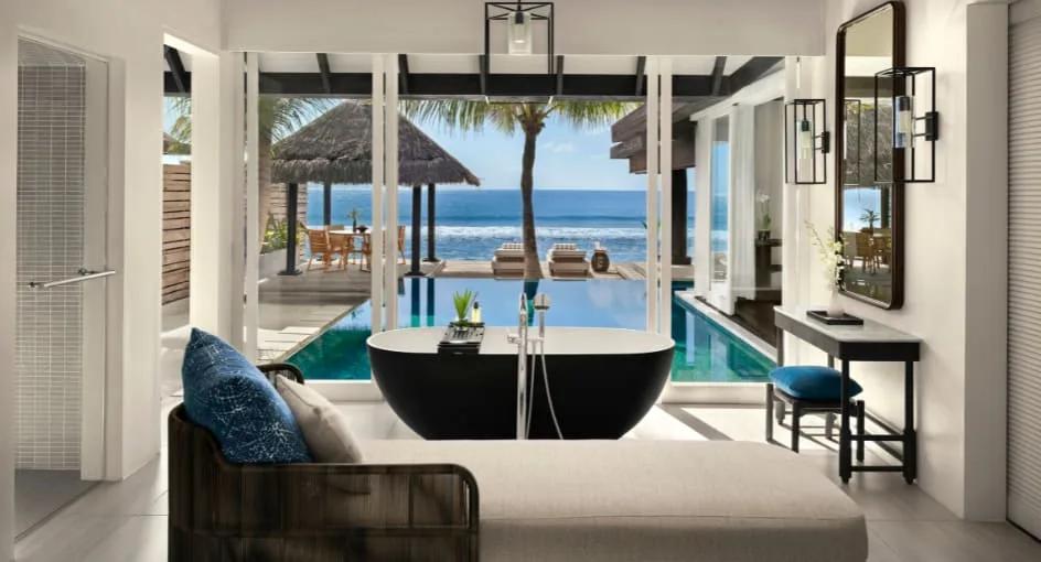 The bathroom of an Ocean House with Pool, a freestanding black tub facing the pool and ocean beyond