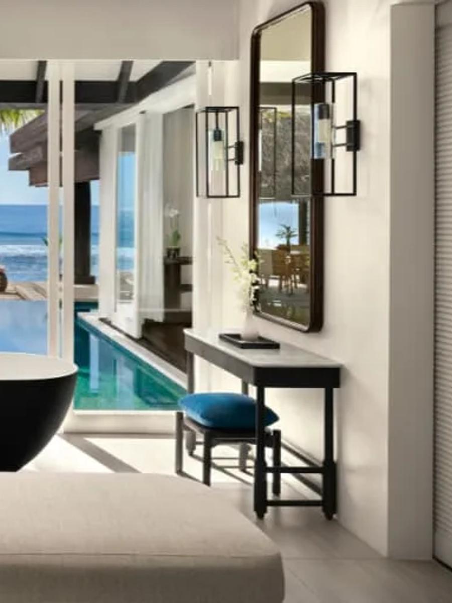 The bathroom of an Ocean House with Pool, a freestanding black tub facing the pool and ocean beyond