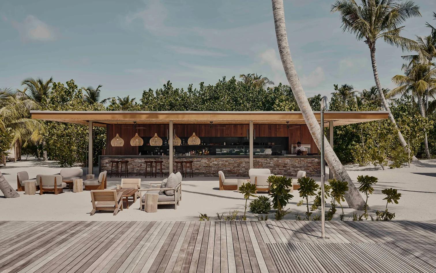 Veli Bar's beachfront counter and lounge seating, shaded by palms on the open sand