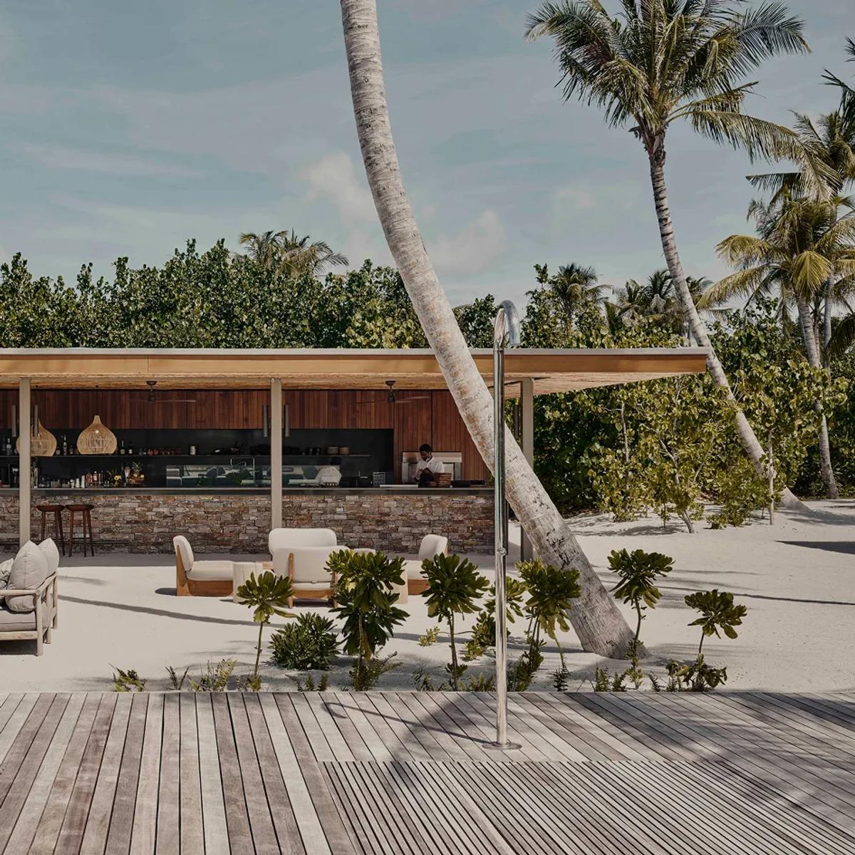 Veli Bar's beachfront counter and lounge seating, shaded by palms on the open sand