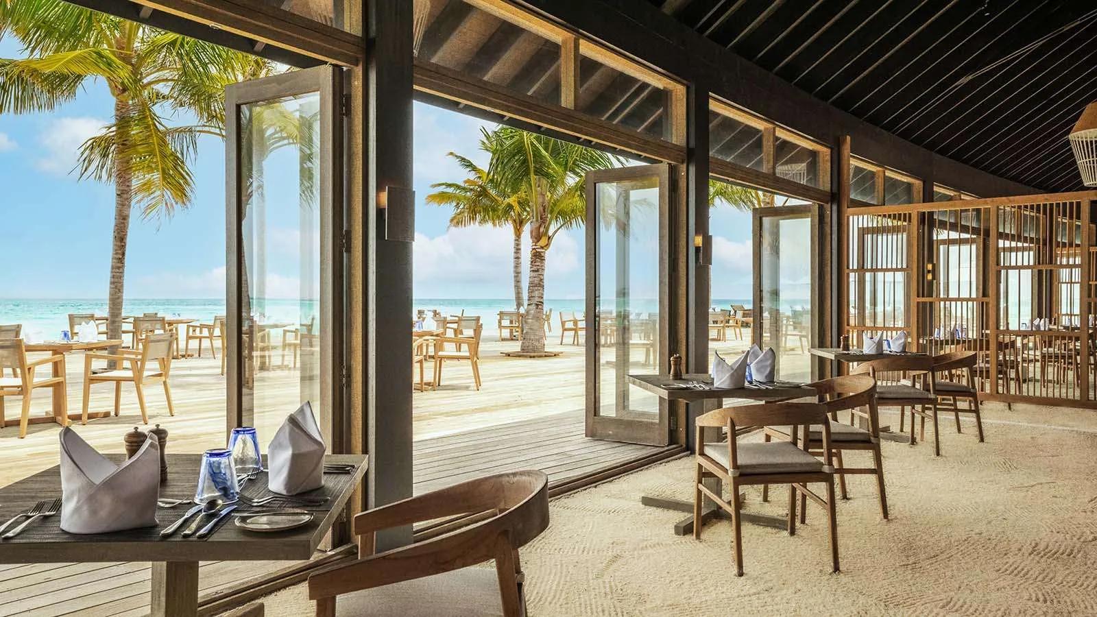 The interior of one of Jawakara's international buffet restaurants, tables set beside open doors to the beach