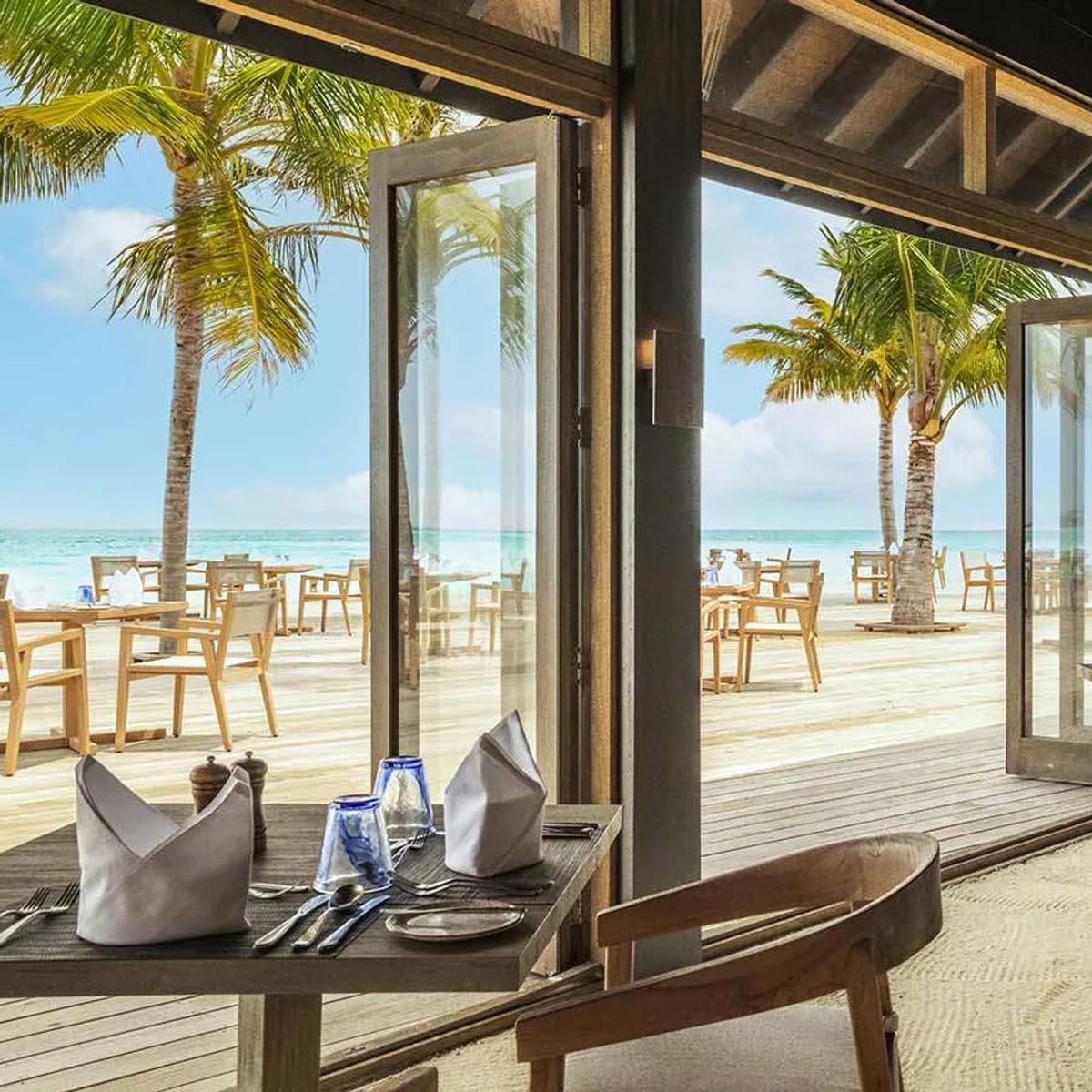 The interior of one of Jawakara's international buffet restaurants, tables set beside open doors to the beach