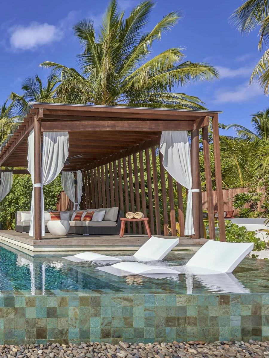 The private plunge pool and curtained outdoor cabana of a Deluxe Beach Pool Villa, framed by palm trees