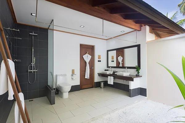 A partially open-air villa bathroom with a rain shower, double vanity and bathrobe