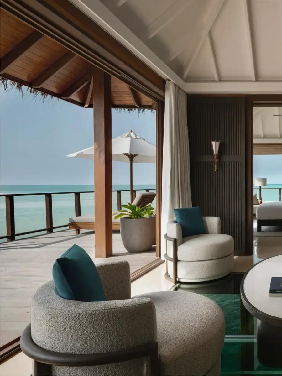 The overwater living room of a Two-Bedroom Rangali Ocean Pavilion, its glass floor panel open to the lagoon below