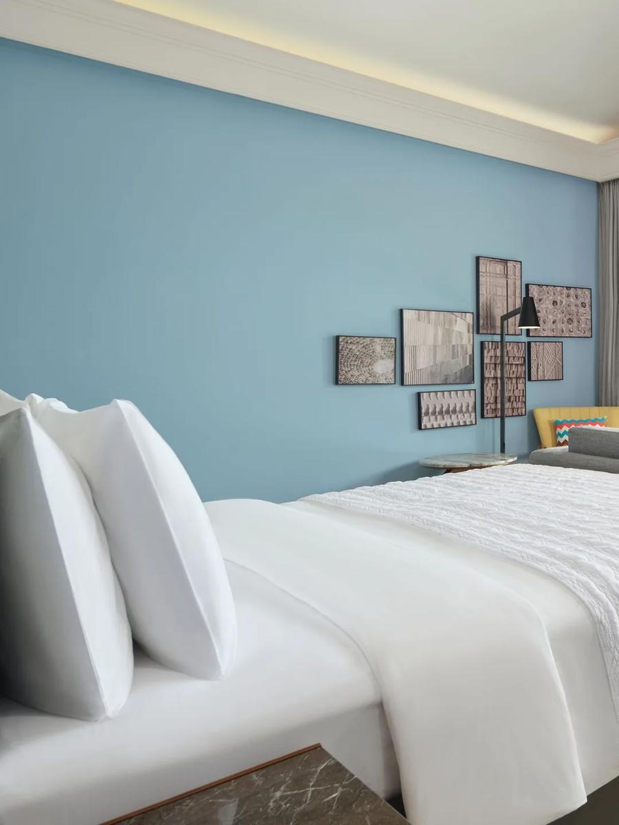 A bedroom inside a Beach Villa opening onto its pool deck at Le Méridien Maldives