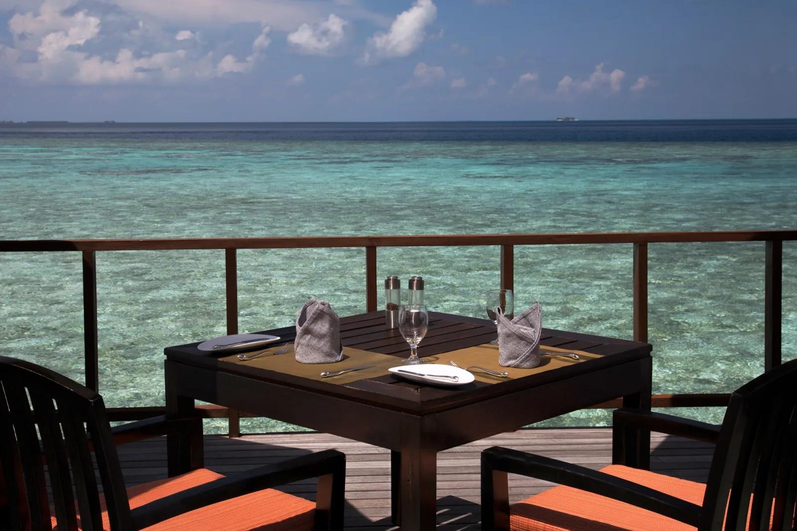 A table set for four on Stars' overwater deck by day, clear turquoise water below
