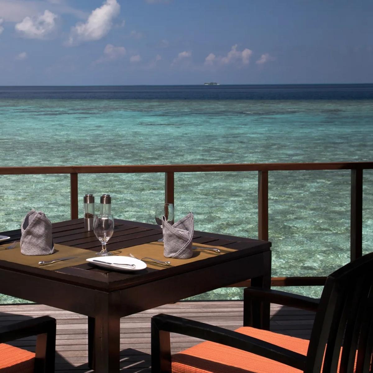 A table set for four on Stars' overwater deck by day, clear turquoise water below