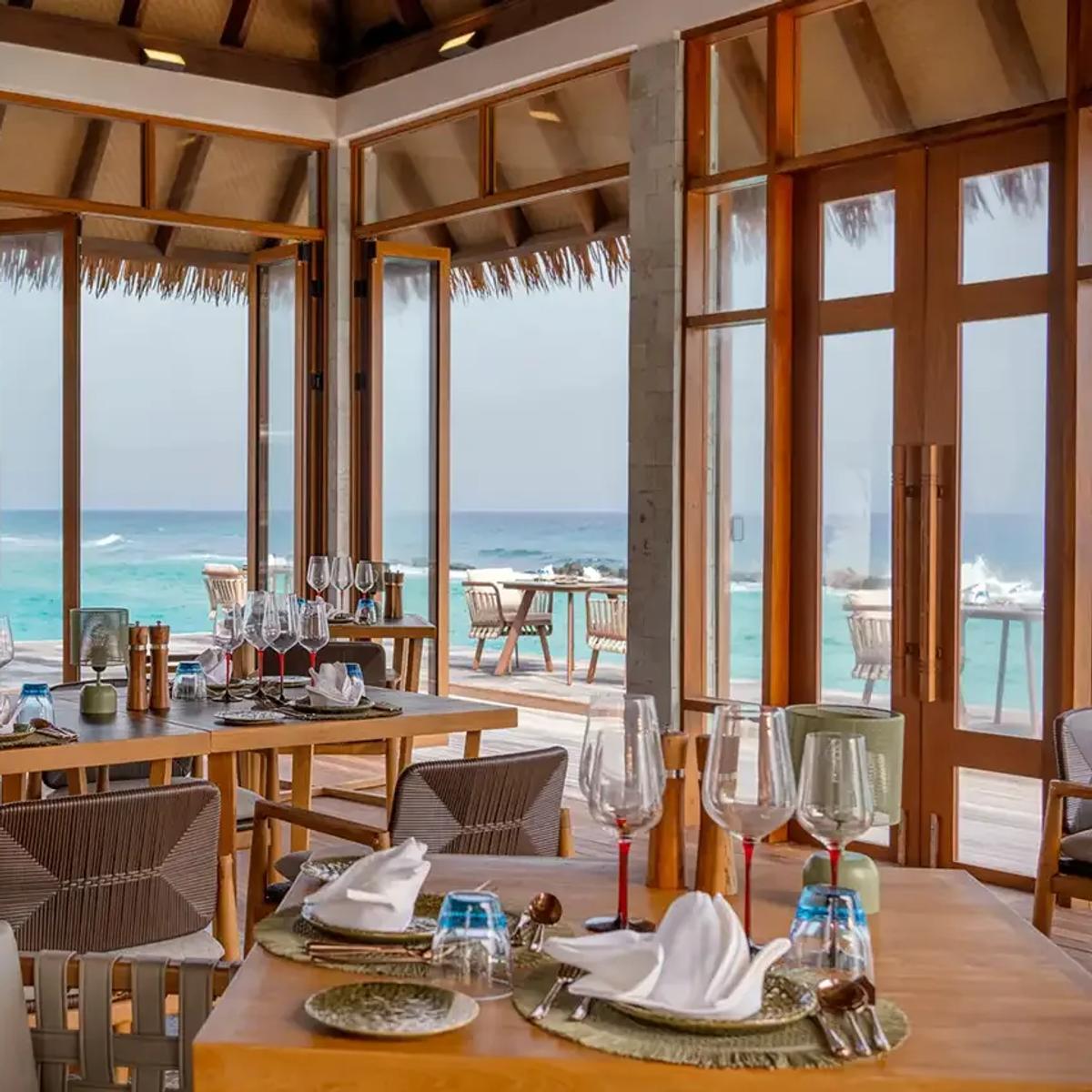 Alif's open-air dining pavilion, tables set with an ocean view