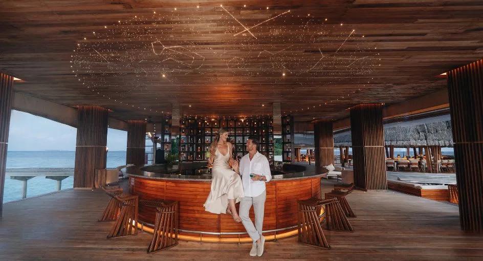 Guests seated at SKY, the overwater observatory lounge, Anantara Kihavah Maldives Villas