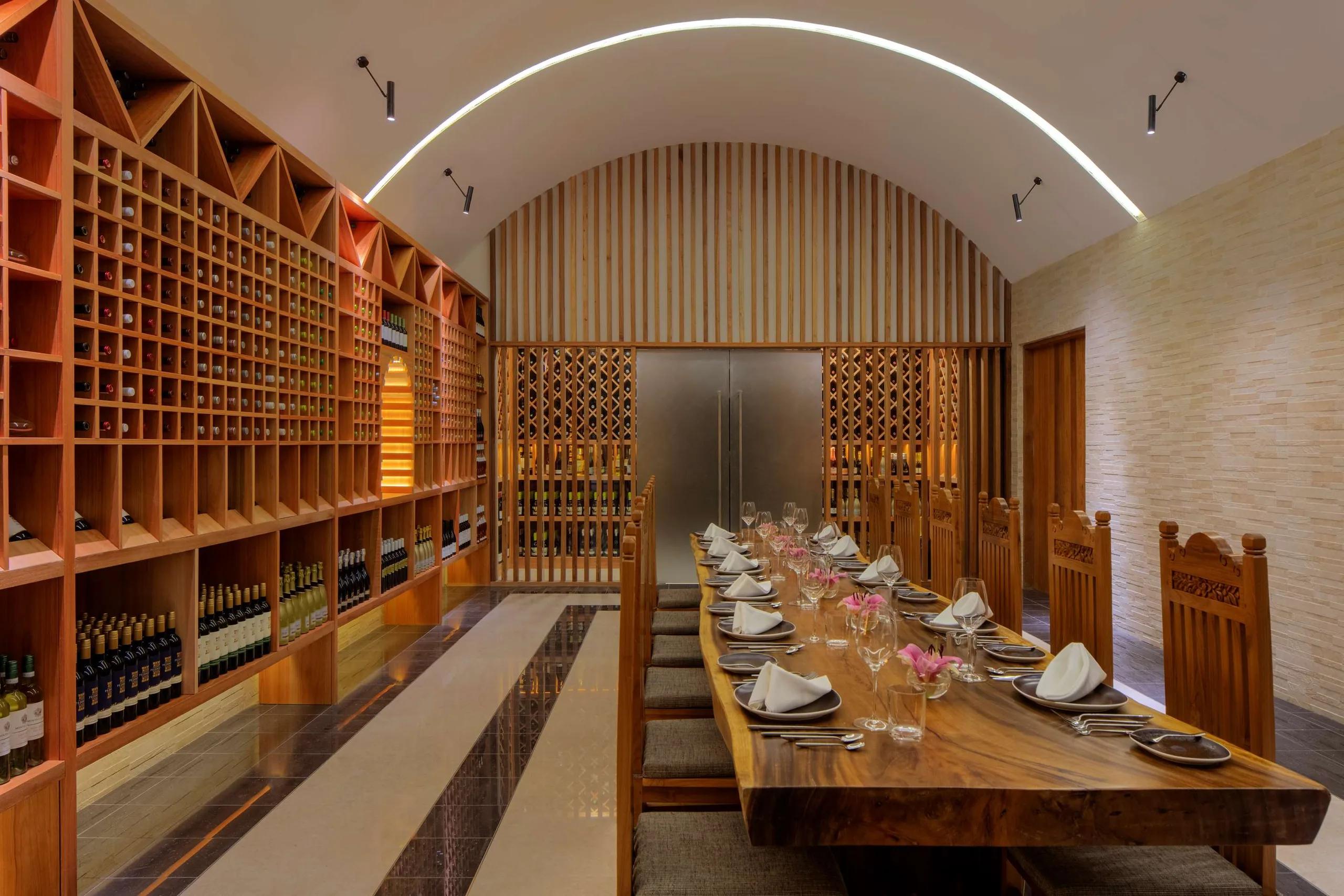 The Lab – Wine Cellar's long dining table at Radisson Blu Resort Maldives, floor-to-ceiling wine racks lining the room