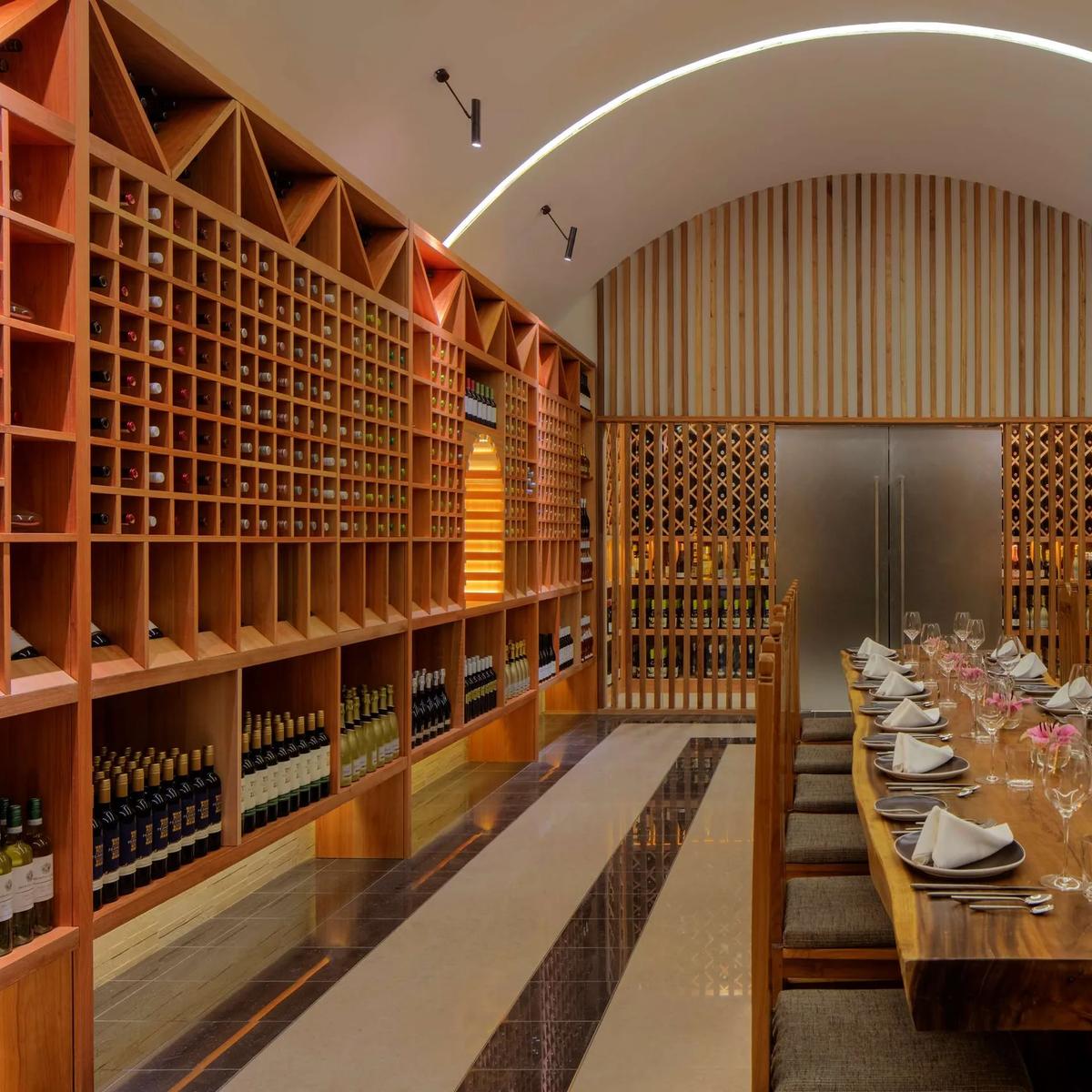 The Lab – Wine Cellar's long dining table at Radisson Blu Resort Maldives, floor-to-ceiling wine racks lining the room