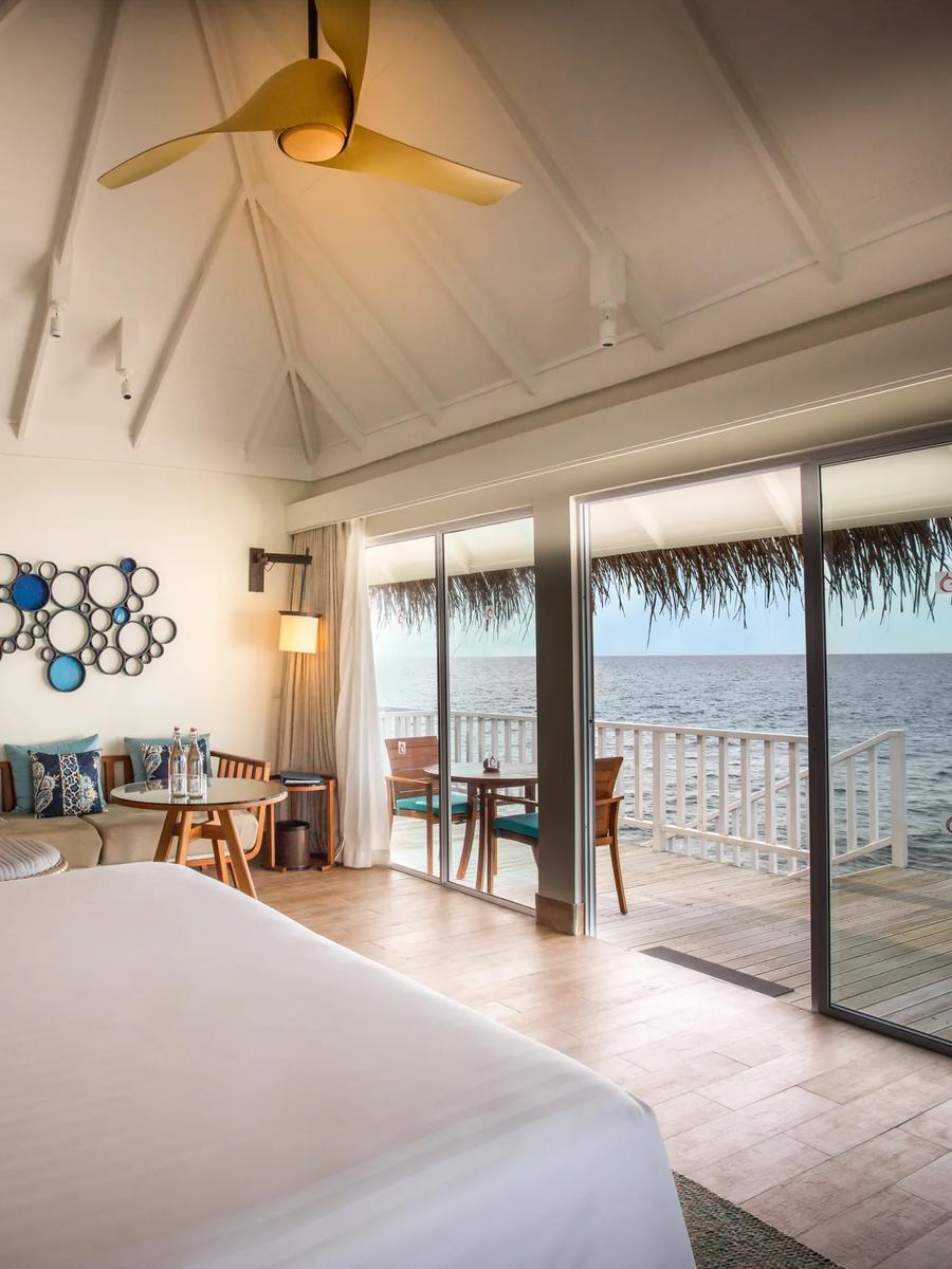 The vaulted thatched ceiling and wooden fan of a Sunrise Overwater Villa's living area