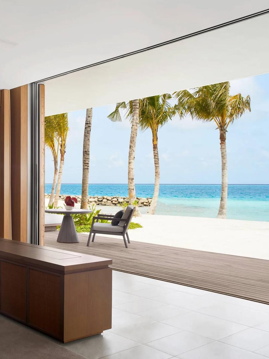 A bedroom in the Two Bedroom Overwater Villa, glass walls opening onto the sea