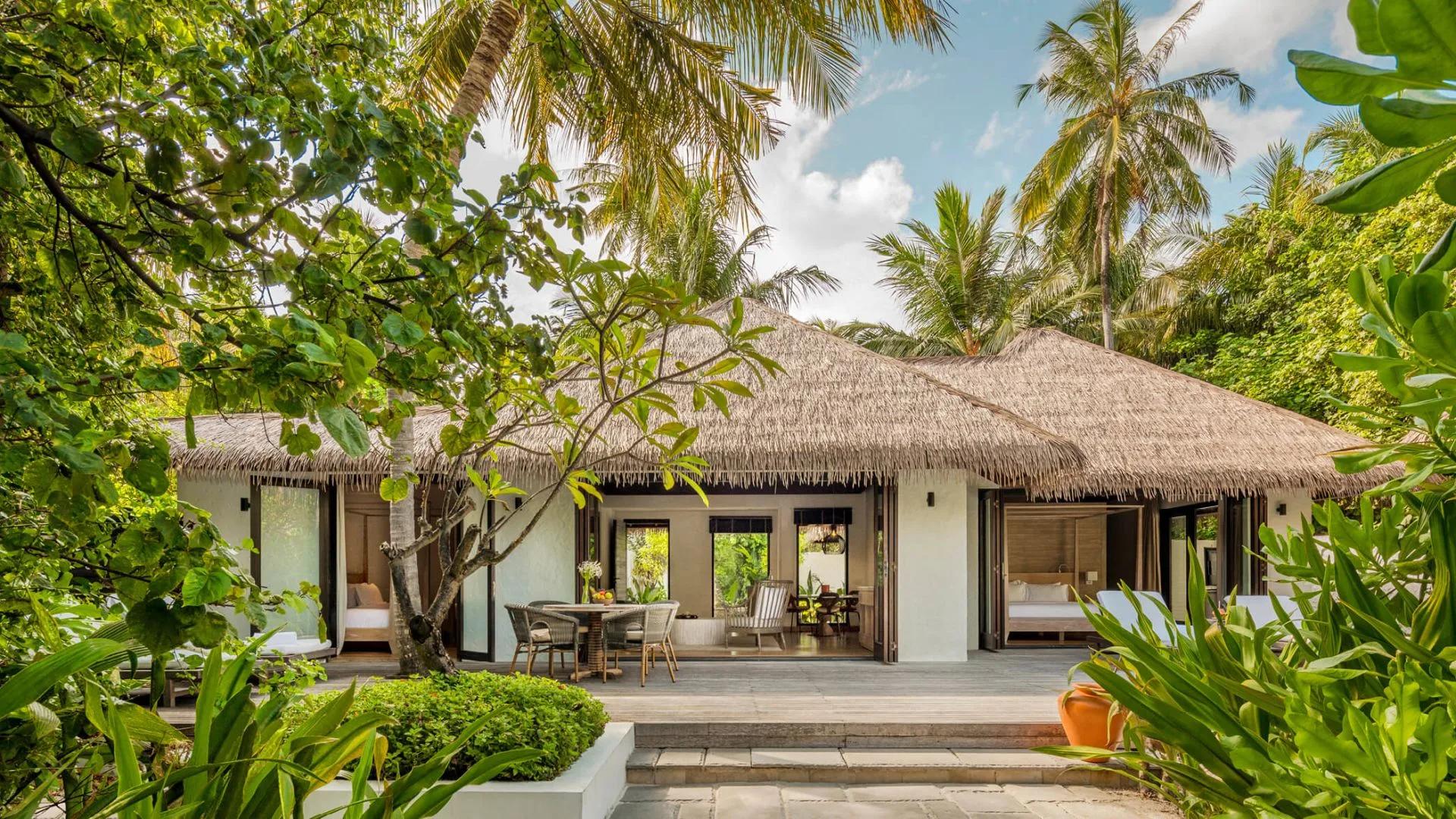 Exterior of a Two-Bedroom Beach Villa among palm trees, with an outdoor dining table on the terrace