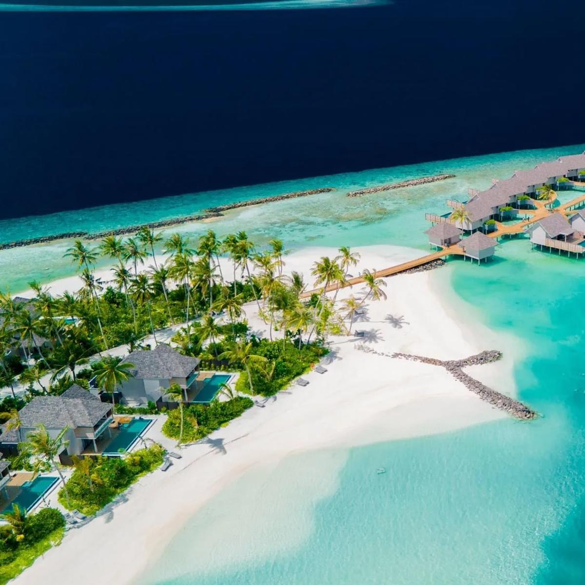 Aerial view of ananea Madivaru Maldives, overwater villas curving into the lagoon beside the beach villas and reef line