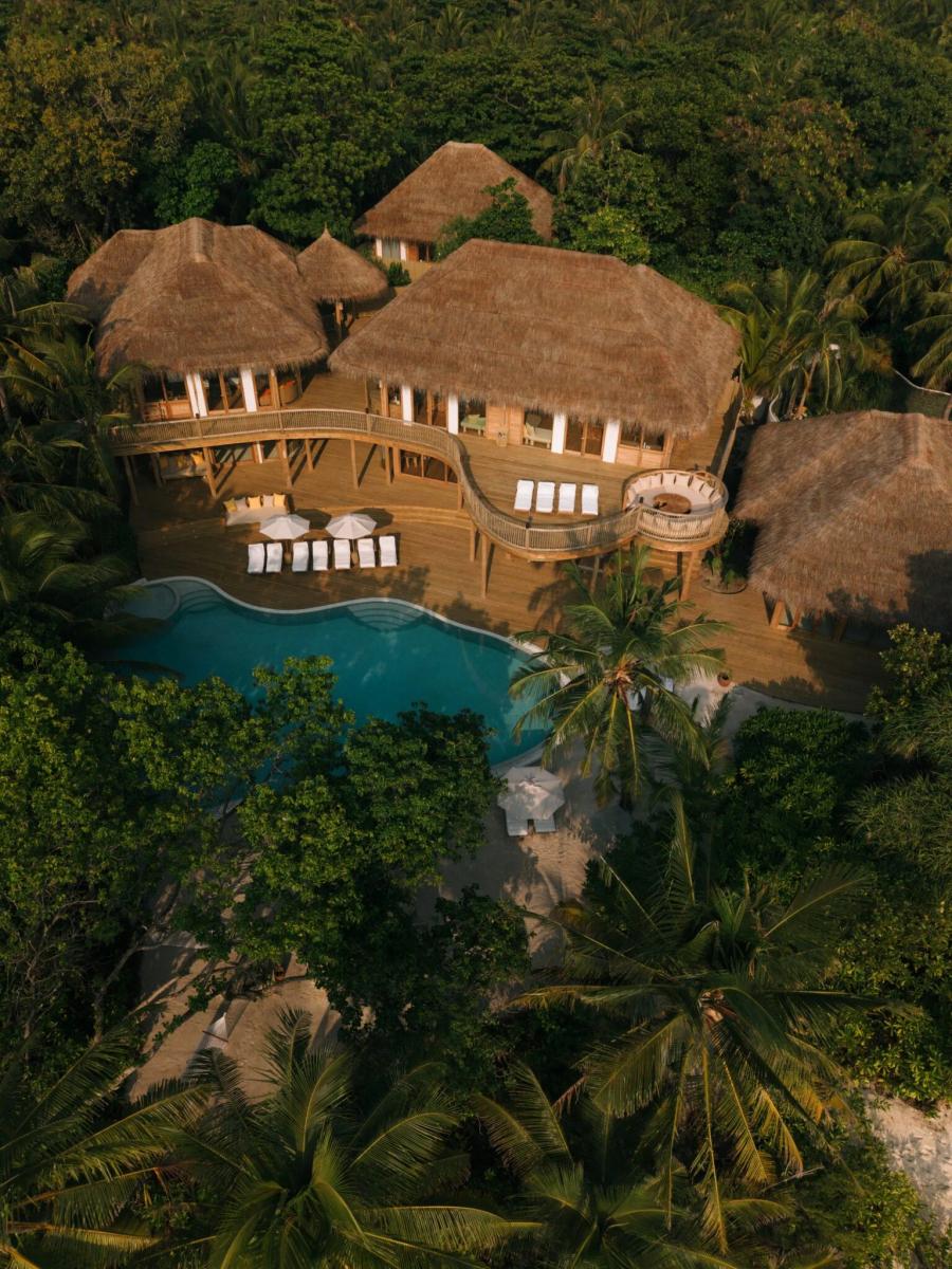 An aerial view of Villa 42's free-form pool and multiple thatched roofs framed by dense palm canopy. Villa 42 is one of the resort's 6-Bedroom Residences, shown here as representative of the similarly scaled Sunset Reserve, for which no dedicated photograph was available in this research batch