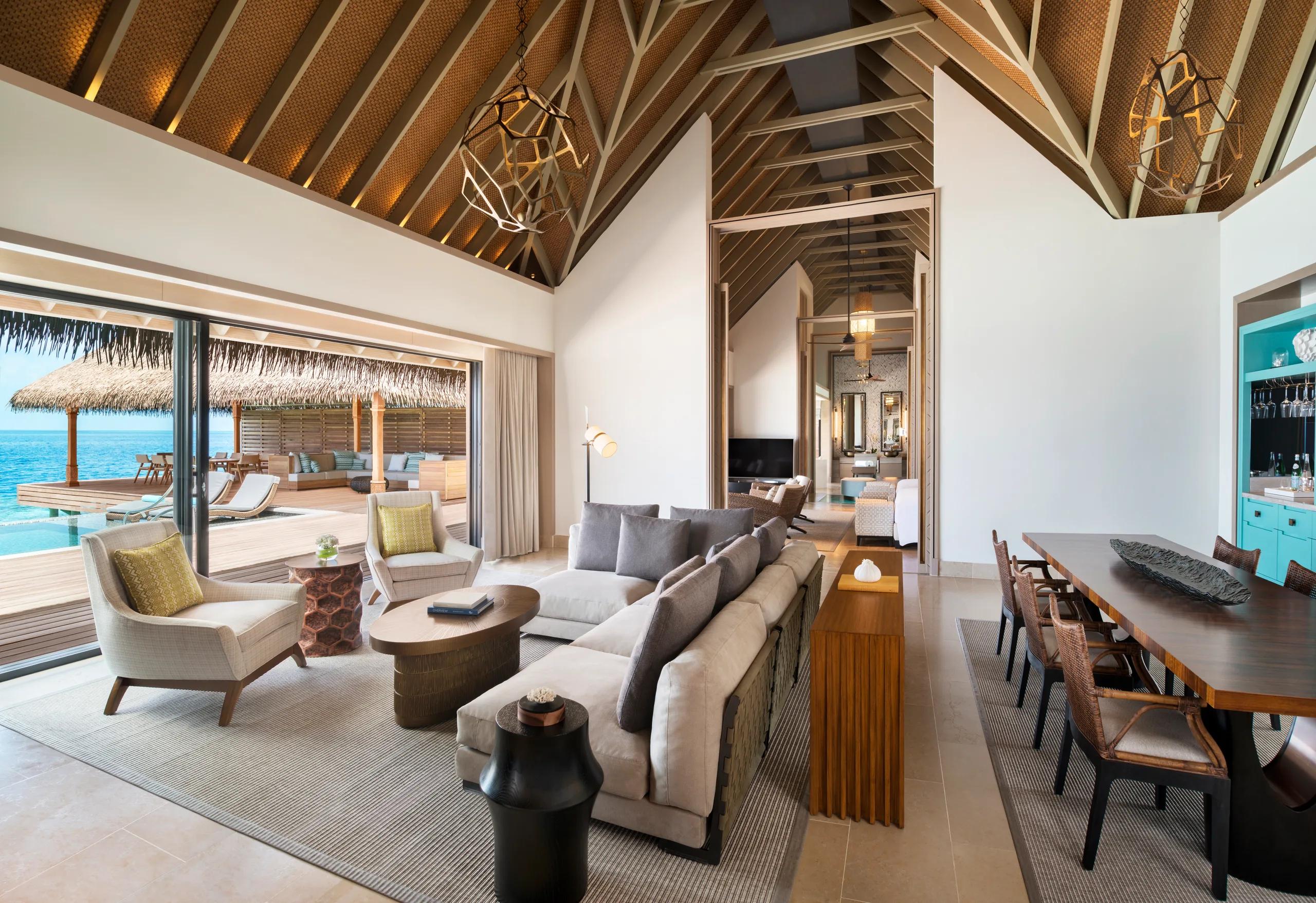 The living and dining area of the Two Bedroom Overwater Villa at Waldorf Astoria Maldives Ithaafushi, opening onto its overwater deck
