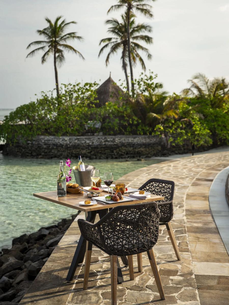 A private dinner table set at the water's edge near Kandu Grill at dusk