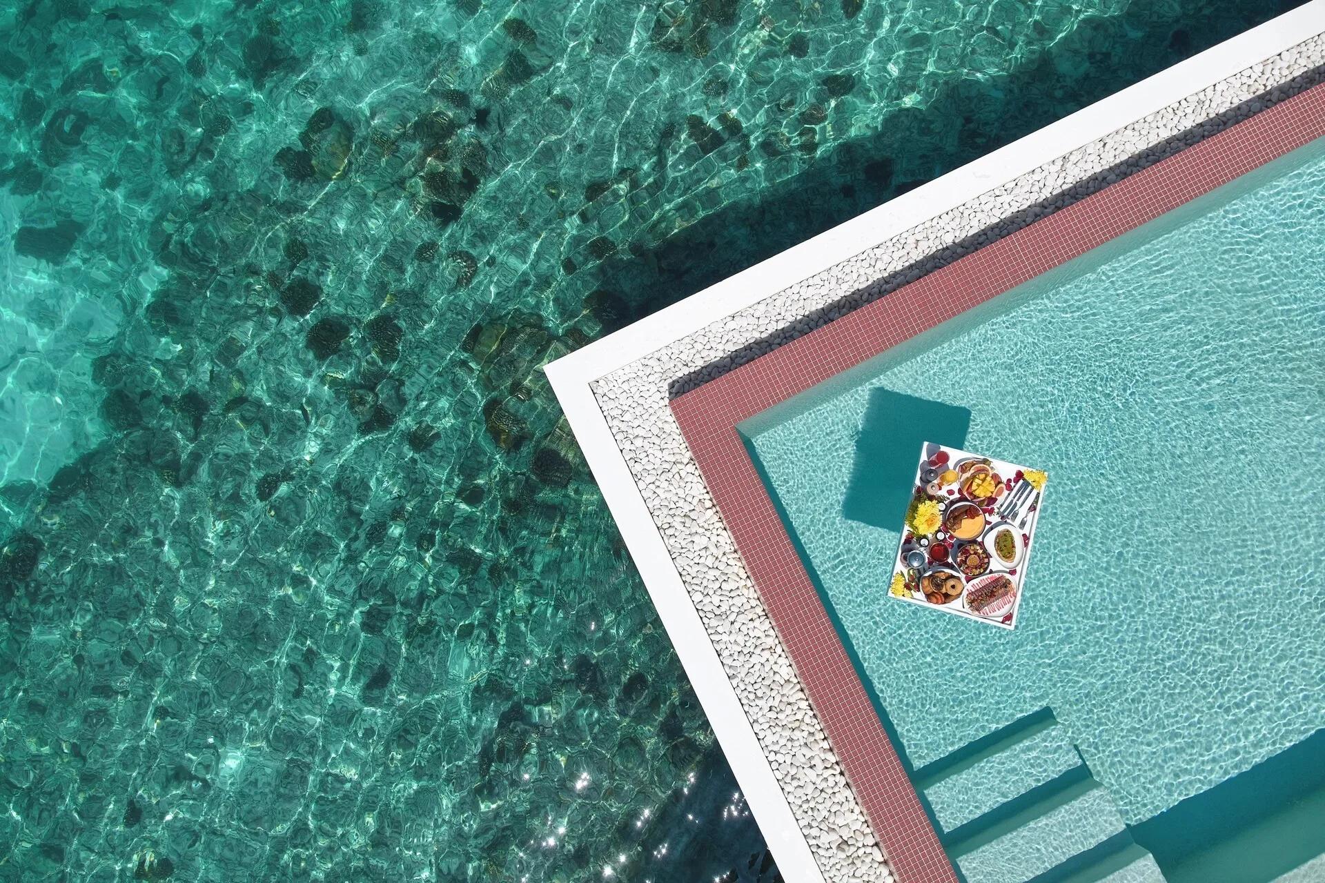 A fruit and pastry breakfast platter floating on a tray in a villa pool, seen from directly above — Gelateria has no dedicated photograph in the source material; this stands in as the closest available food-styling shot