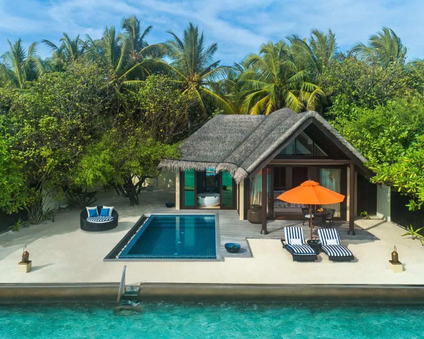 A Sunrise Oceanfront Villa with Pool's exterior, a private rectangular pool and orange umbrella set among coconut palms