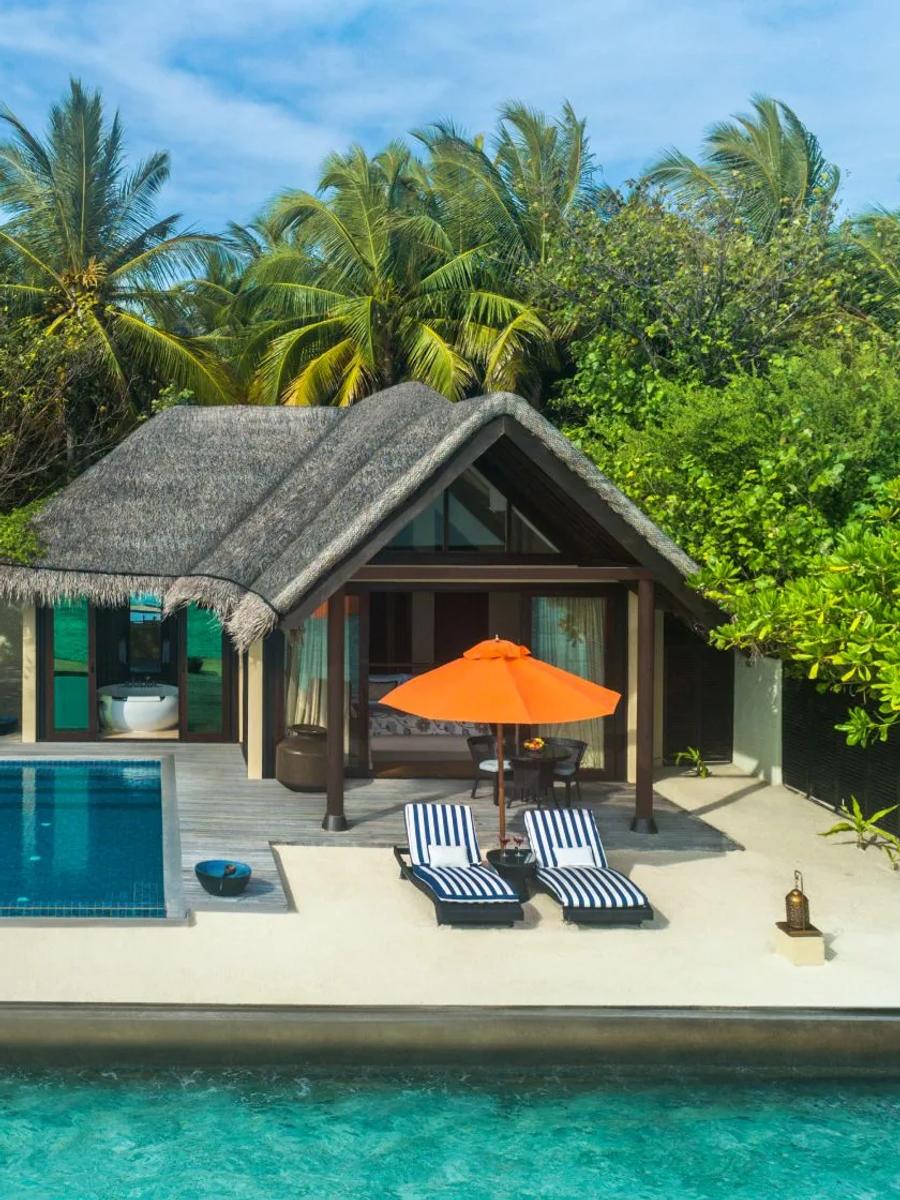 A Sunrise Oceanfront Villa with Pool's exterior, a private rectangular pool and orange umbrella set among coconut palms