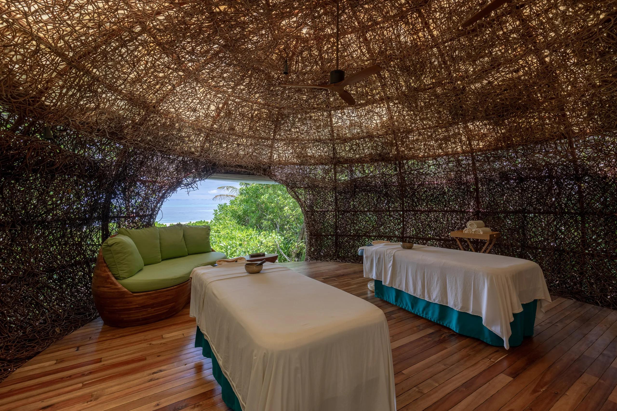 A woven rattan ceiling inside a spa treatment room, lit from within with a ceiling fan turning