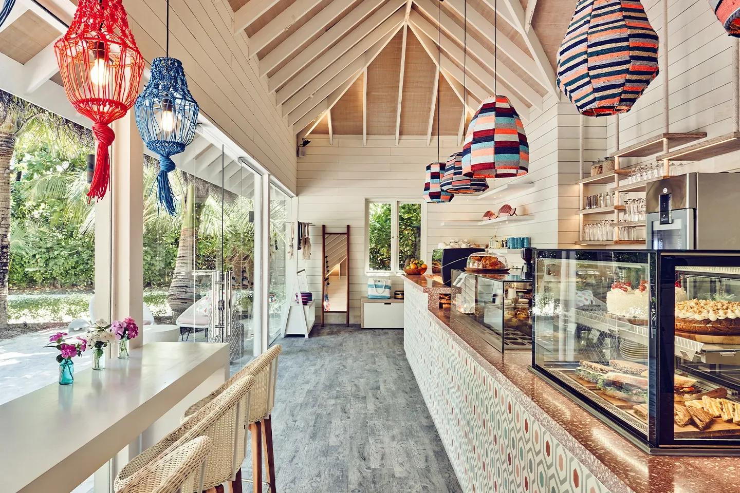 Milk LAB's counter hung with colourful woven pendant lights, its display case stocked with cakes and sandwiches