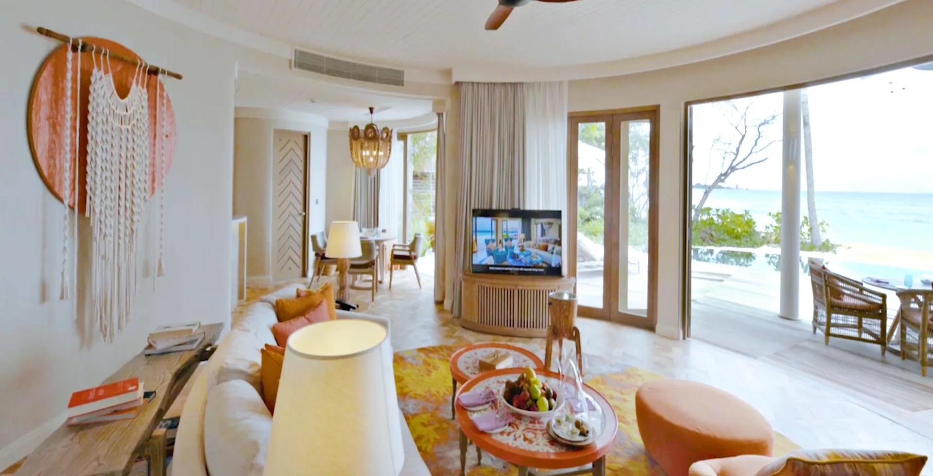 A Two-Bedroom Beach Residence living room with an orange macrame wall hanging, opening onto its own deck.