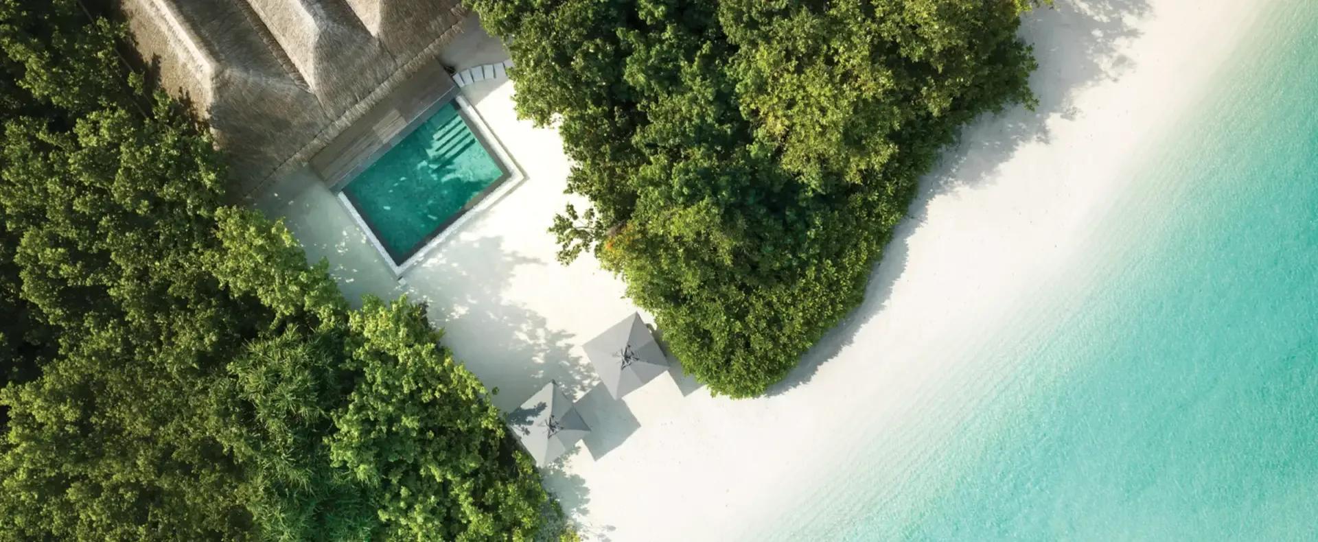 Aerial view of a Two Bedroom Beach Pool Residence's private pool, sun loungers and umbrellas on the sand beside it