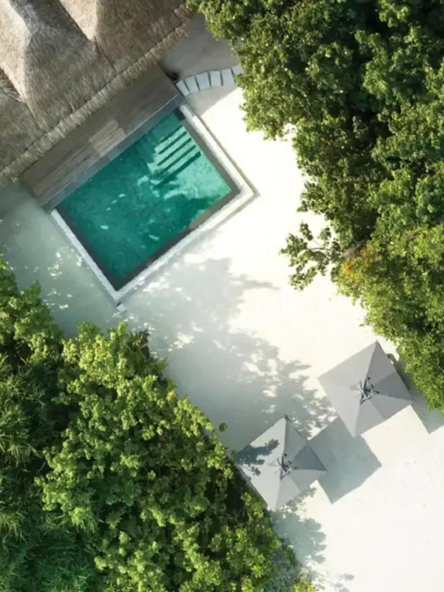 Aerial view of a Two Bedroom Beach Pool Residence's private pool, sun loungers and umbrellas on the sand beside it