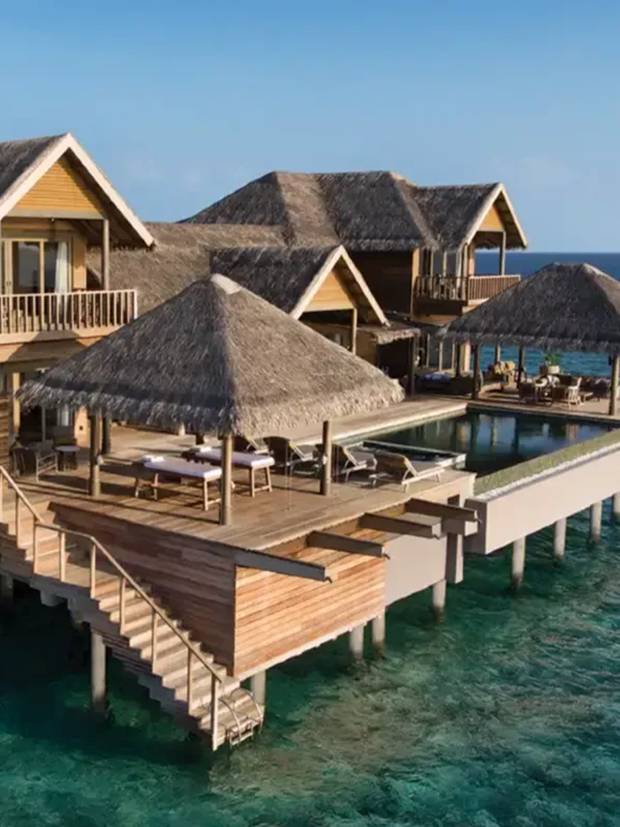 Aerial view of the Vakkaru Over Water Residence, its multiple thatched pavilions and pool built out over the reef