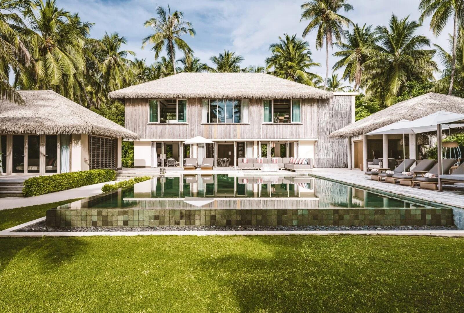 A twin-bed bedroom inside the Royal Beachfront Residence, glass doors open to palm trees and the beach