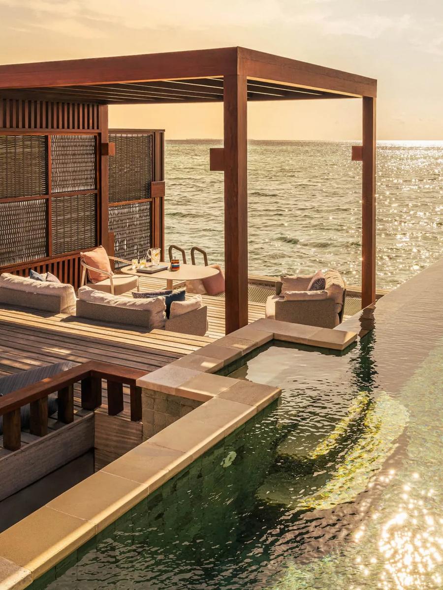 The plunge pool and deck of a Sunset Water Villa, open directly onto the ocean at sunset