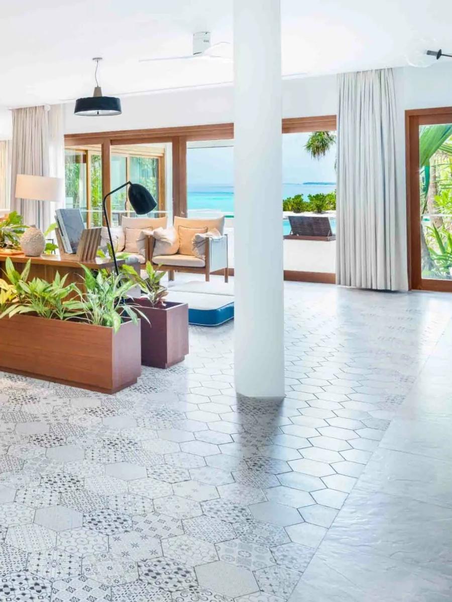 The dining and living area of a Four-Bedroom Beach Residence at Amilla, with the pool and ocean visible through the windows