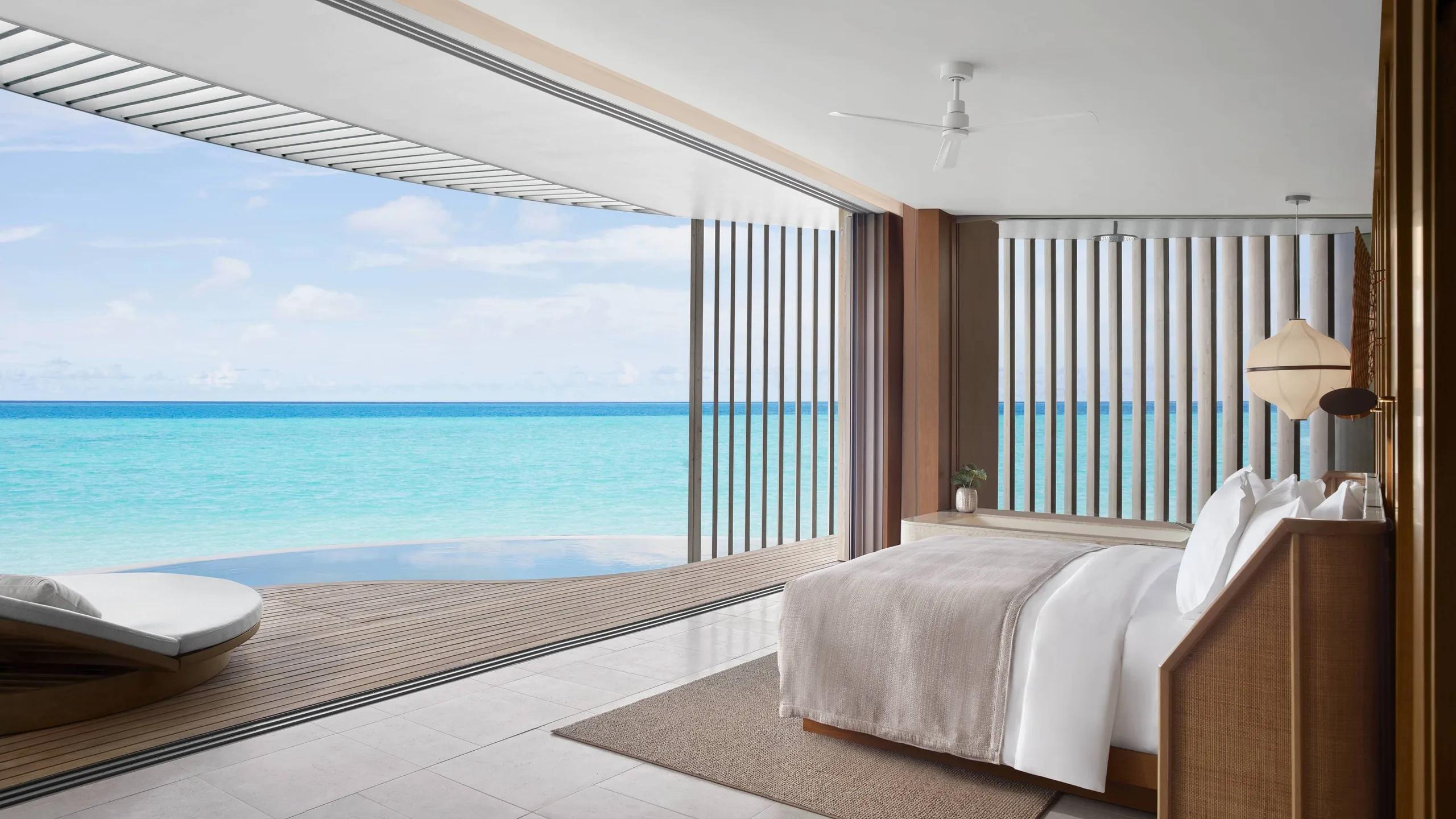 An Ocean Pool Villa bedroom opening onto a private infinity pool and the sea