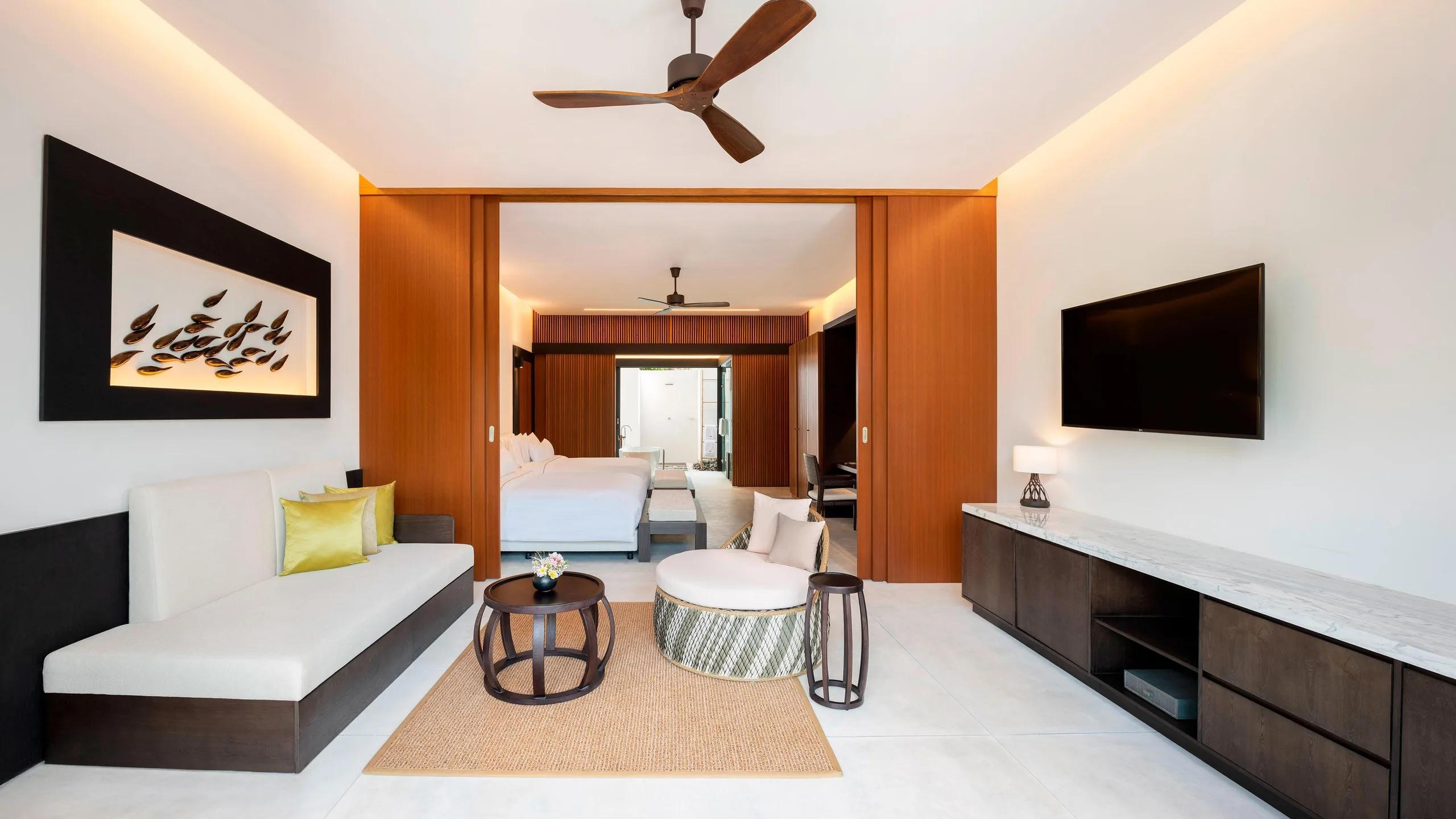 The private living room of a Two-Bedroom Villa with Pool, sliding wood doors open to the bedroom beyond