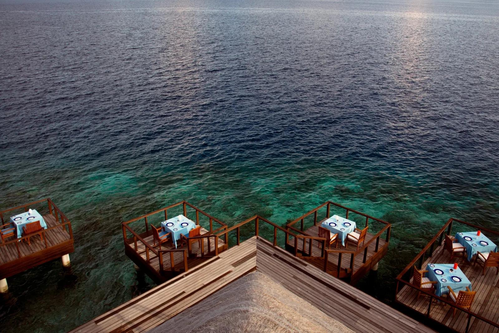Four separate overwater dining platforms extending from Aqua restaurant over the reef