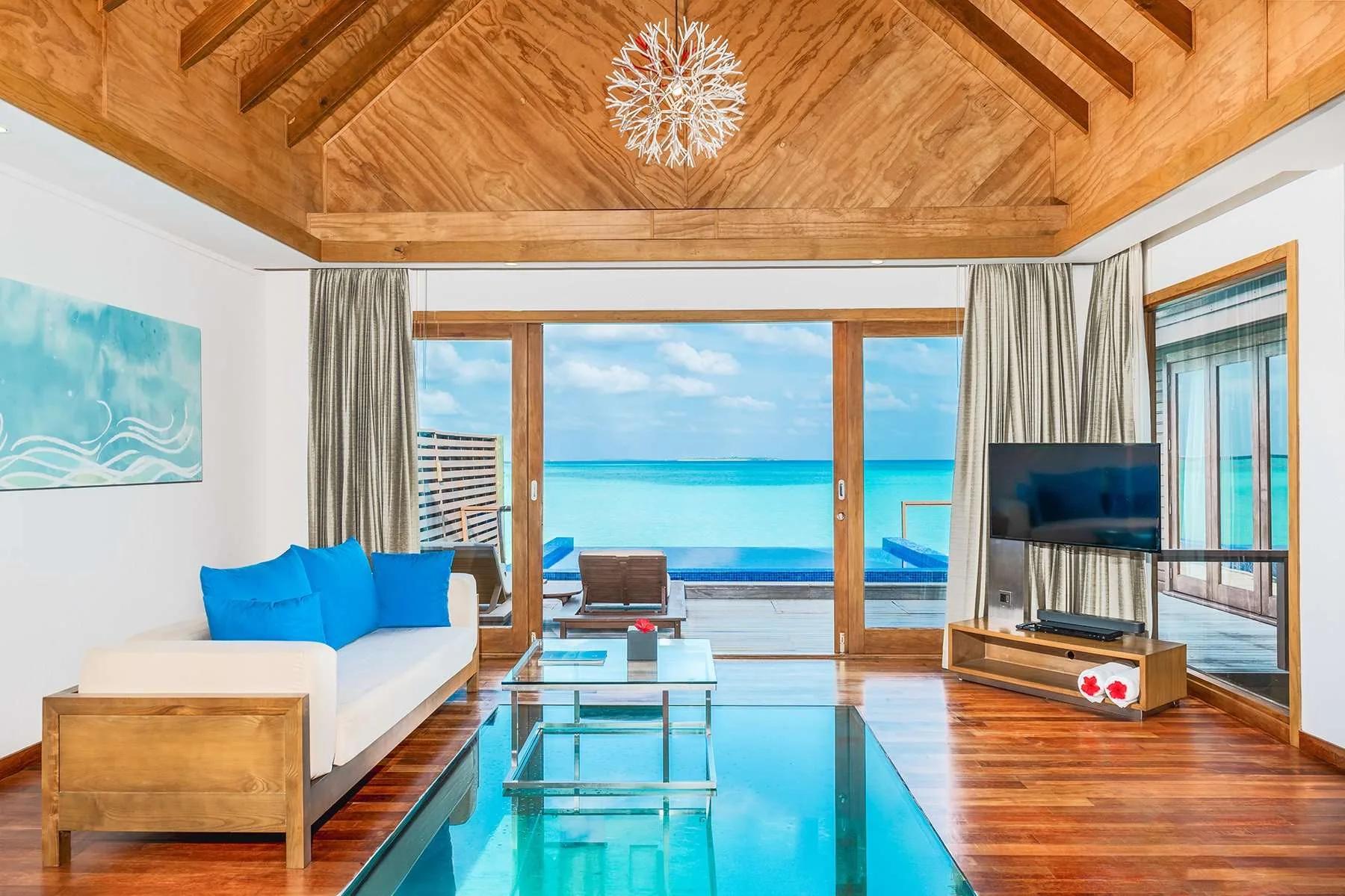 Living room of a Two-Bedroom Ocean Villa with Pool, its glass floor panel open to the lagoon below