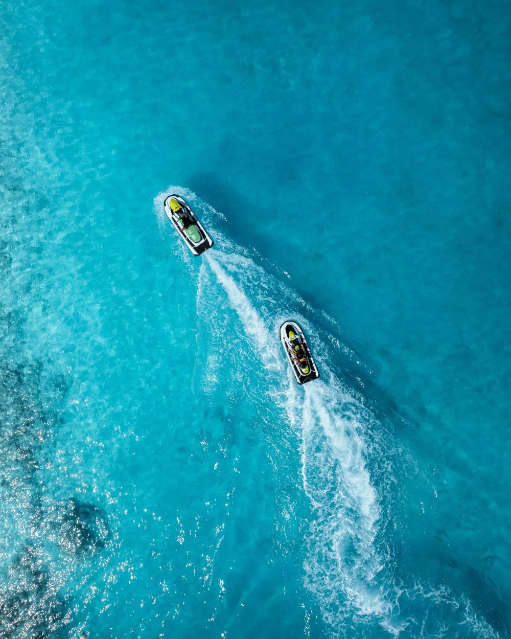Two jet skis crossing the private lagoon at Radisson Blu Resort Maldives, seen directly from above